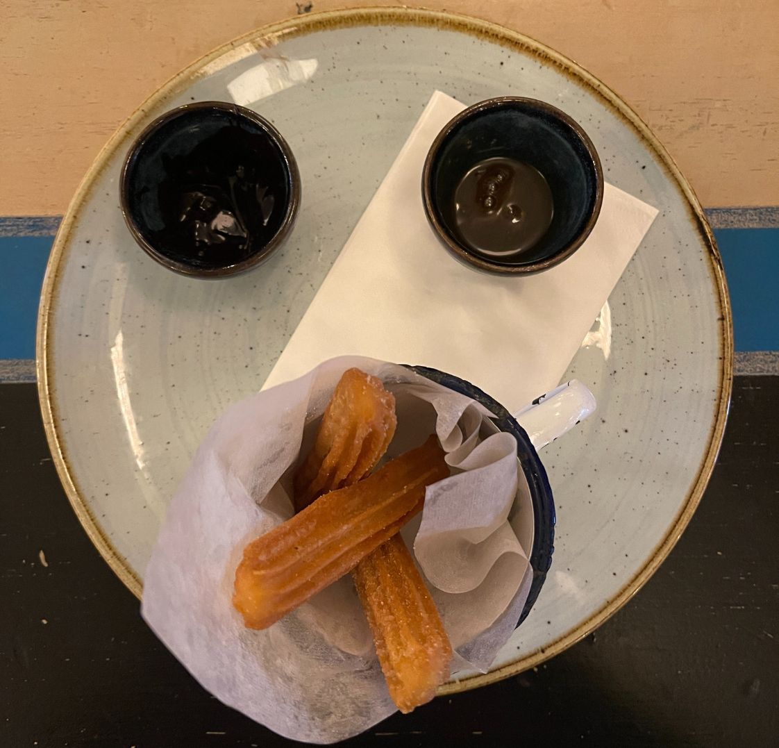Plate of churros with dipping sauces arranged like a smiling face, representing a light-hearted break moment.